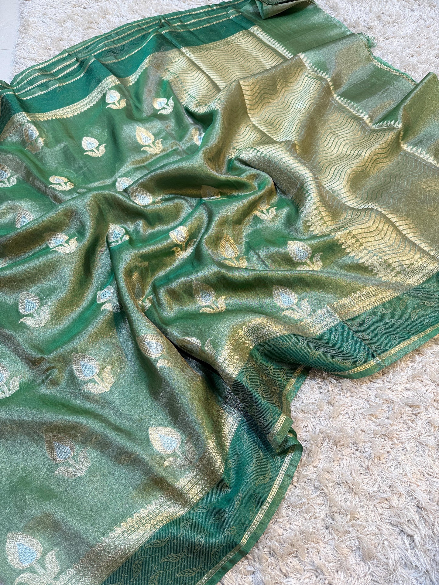 Green fabric with gold patterns on a beige surface