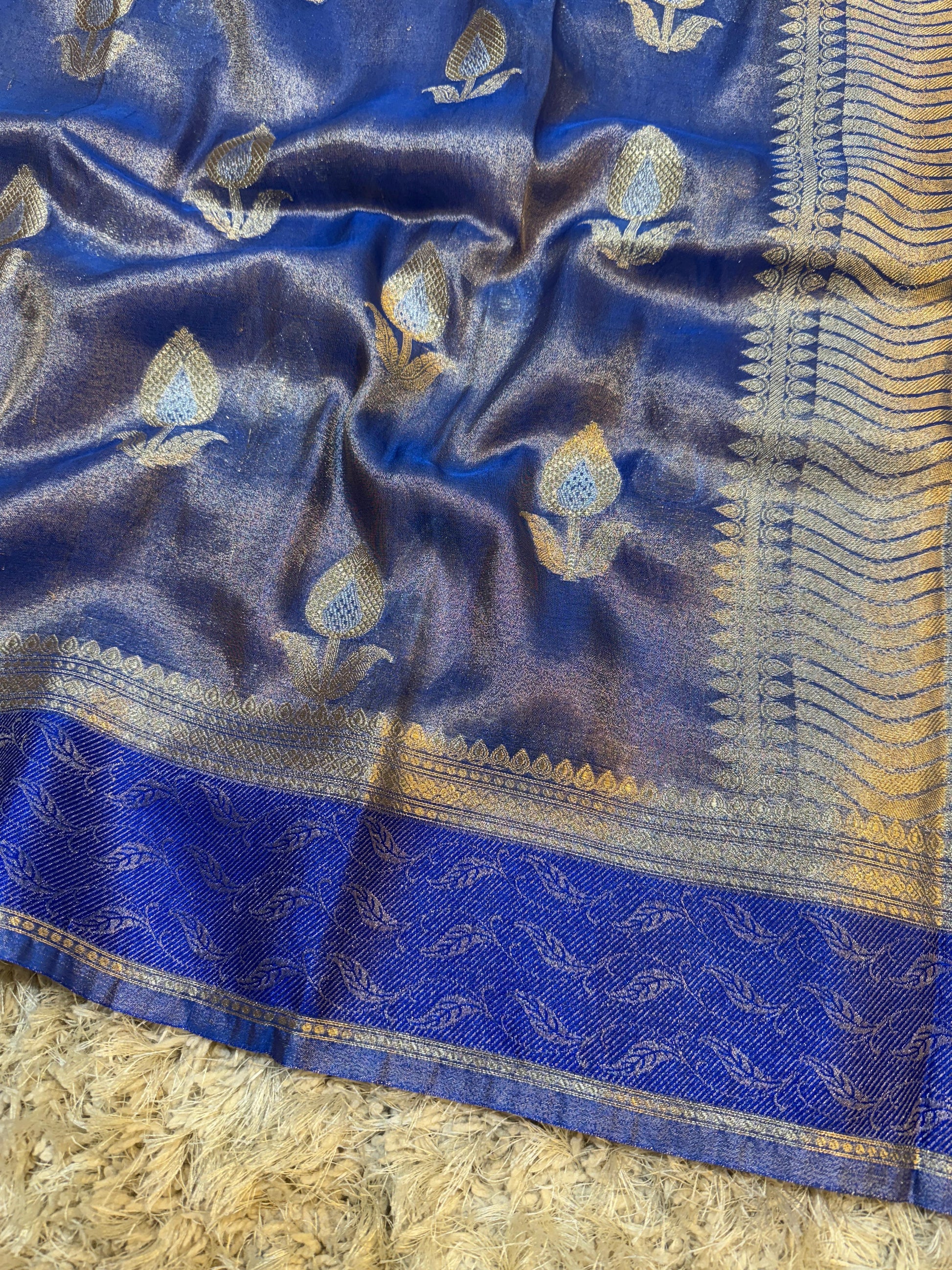 Blue fabric with gold and white patterns on a textured surface