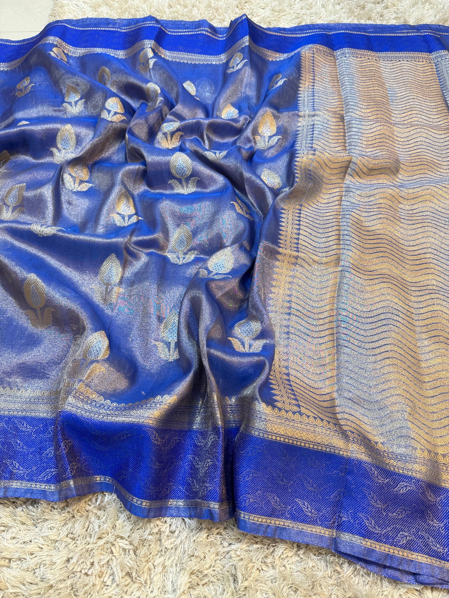 Blue and gold saree with intricate patterns on a textured surface