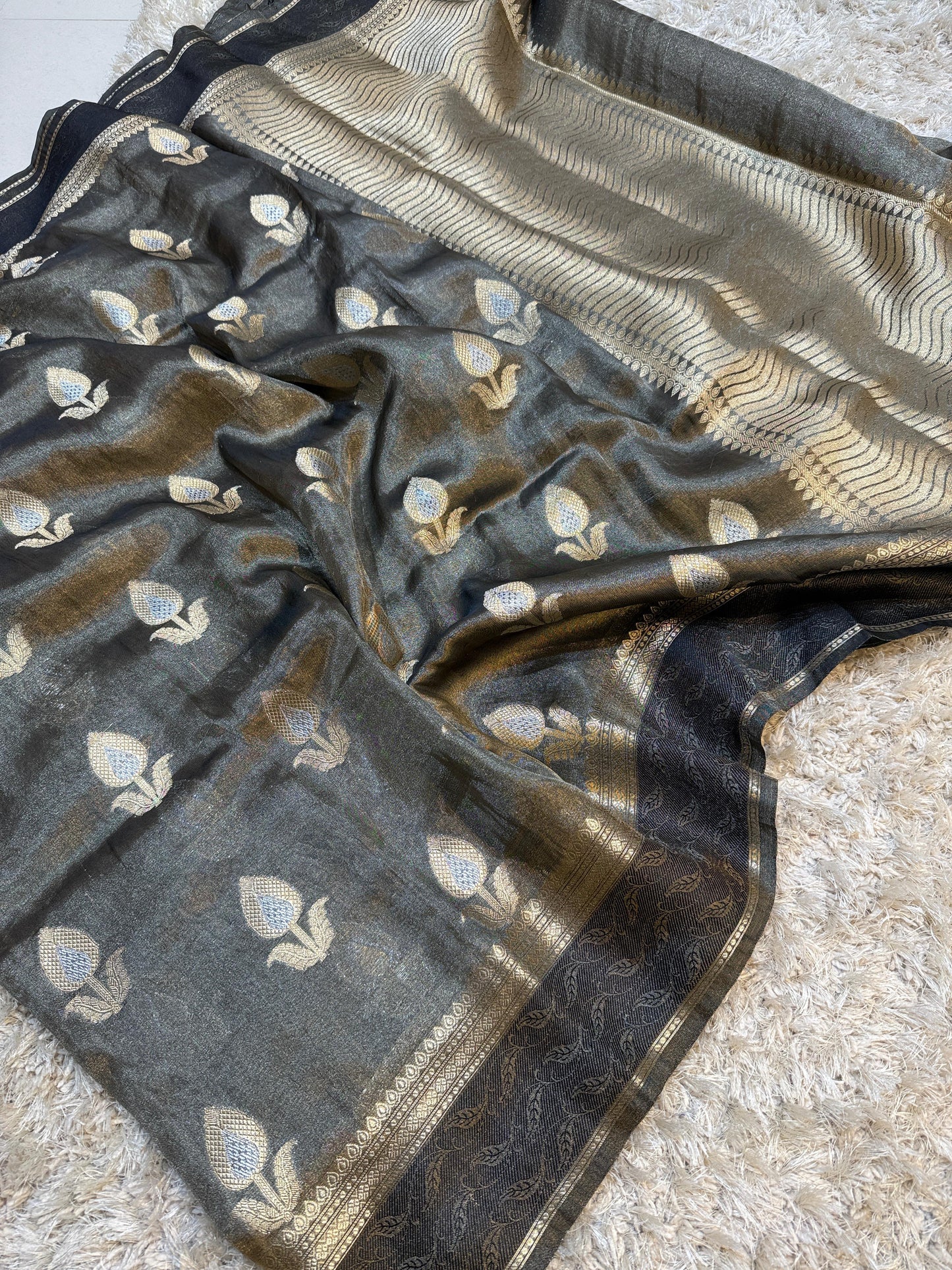 Dark gray fabric with gold and white floral patterns on a textured surface