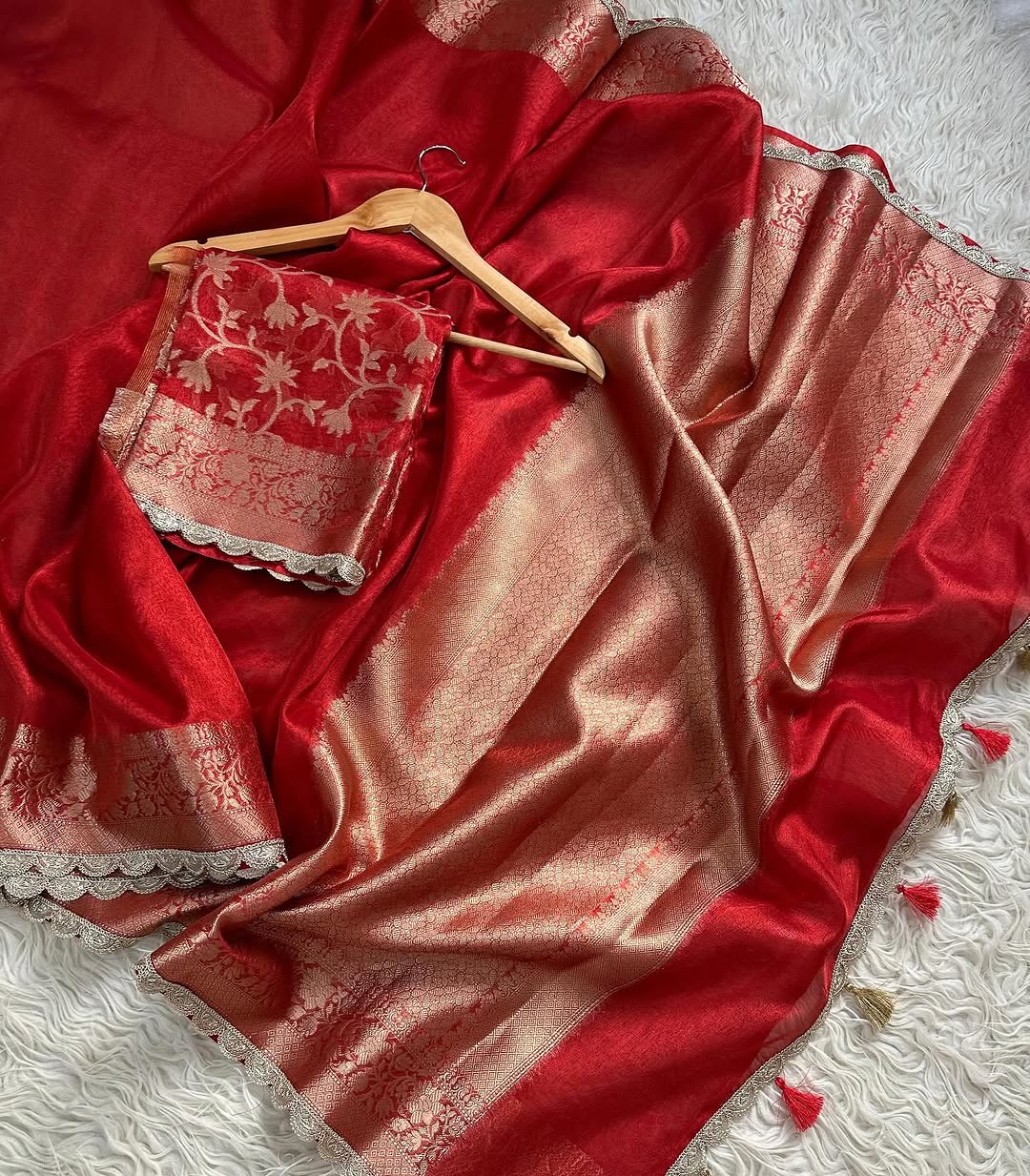 Red and gold saree with a hanger on a textured surface