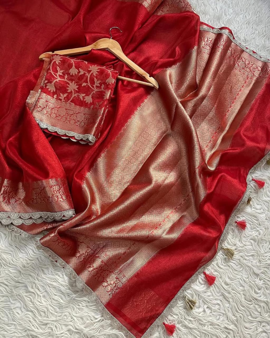 Red saree with gold border draped over a white textured surface