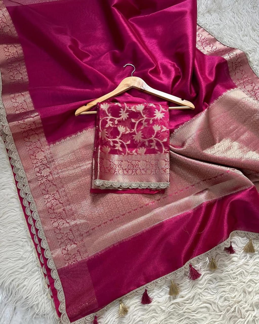 Pink saree with intricate patterns on a white textured surface