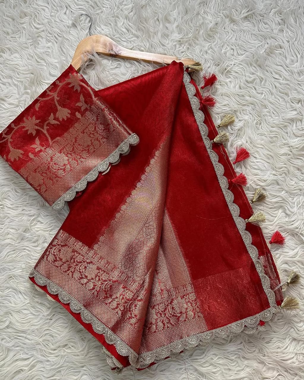 Red saree with white lace details on a textured white background