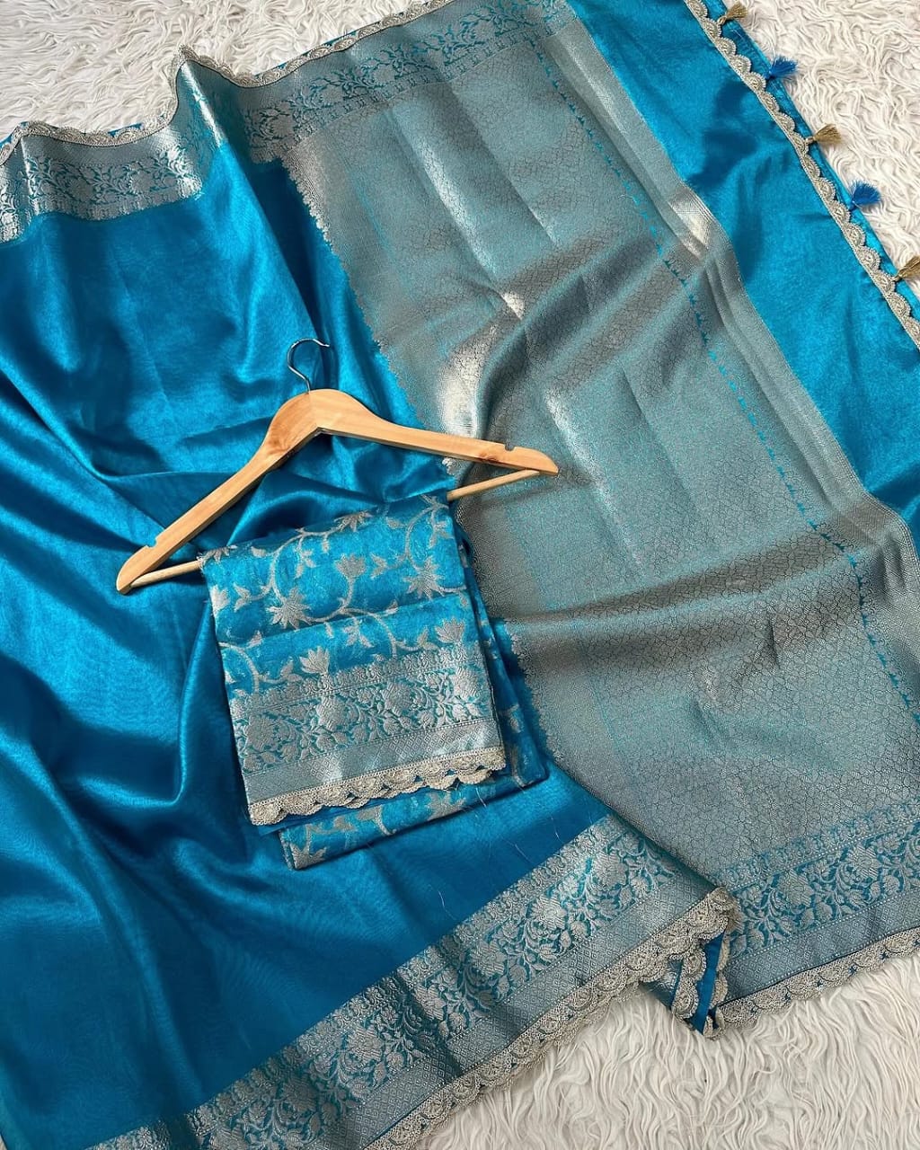 Blue saree with silver embroidery on a hanger against a textured white background