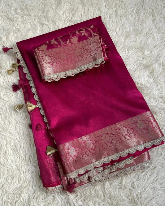 Pink saree with intricate patterns and tassels on a textured white background