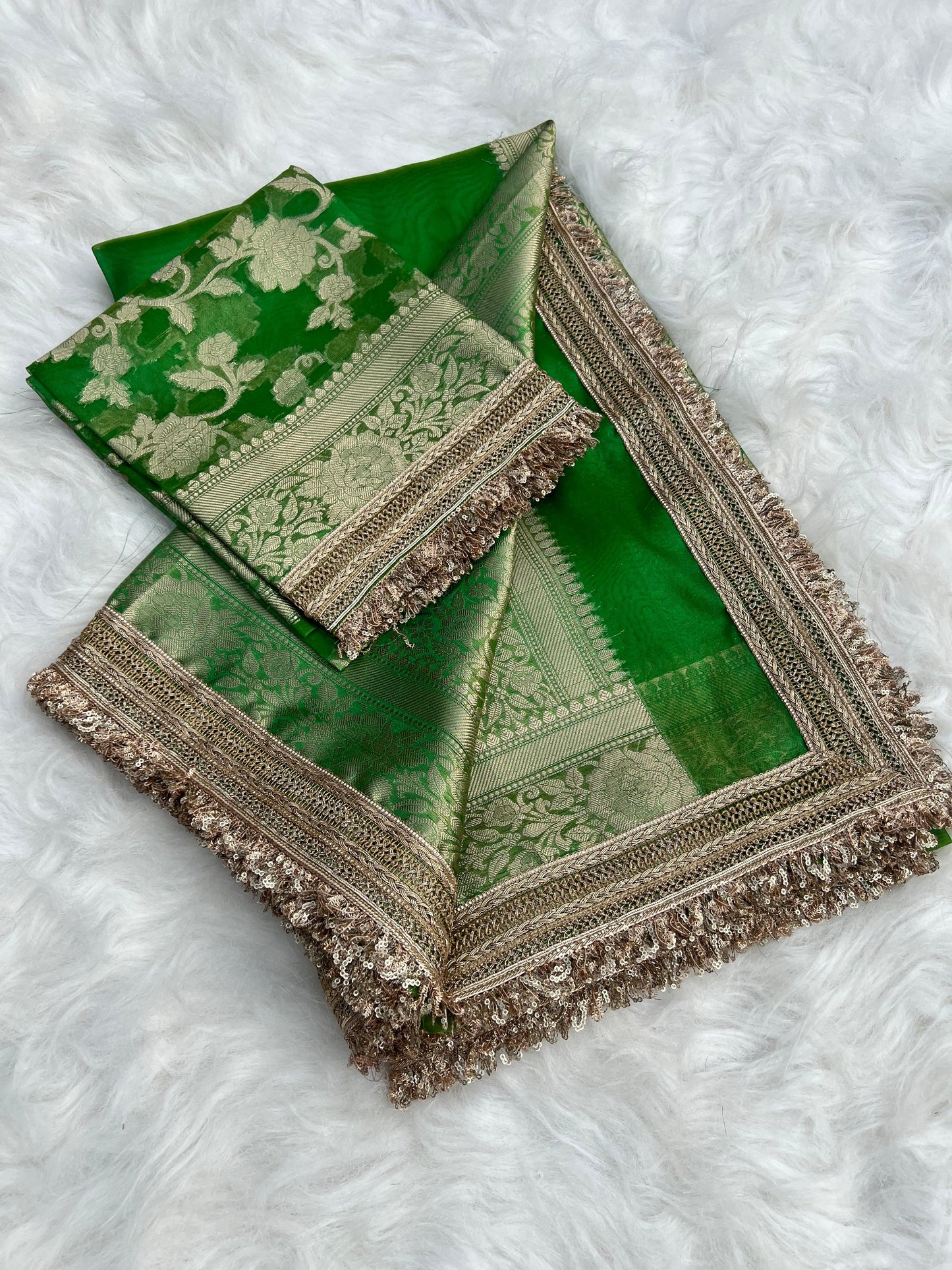 Green saree with gold embroidery on a white textured background