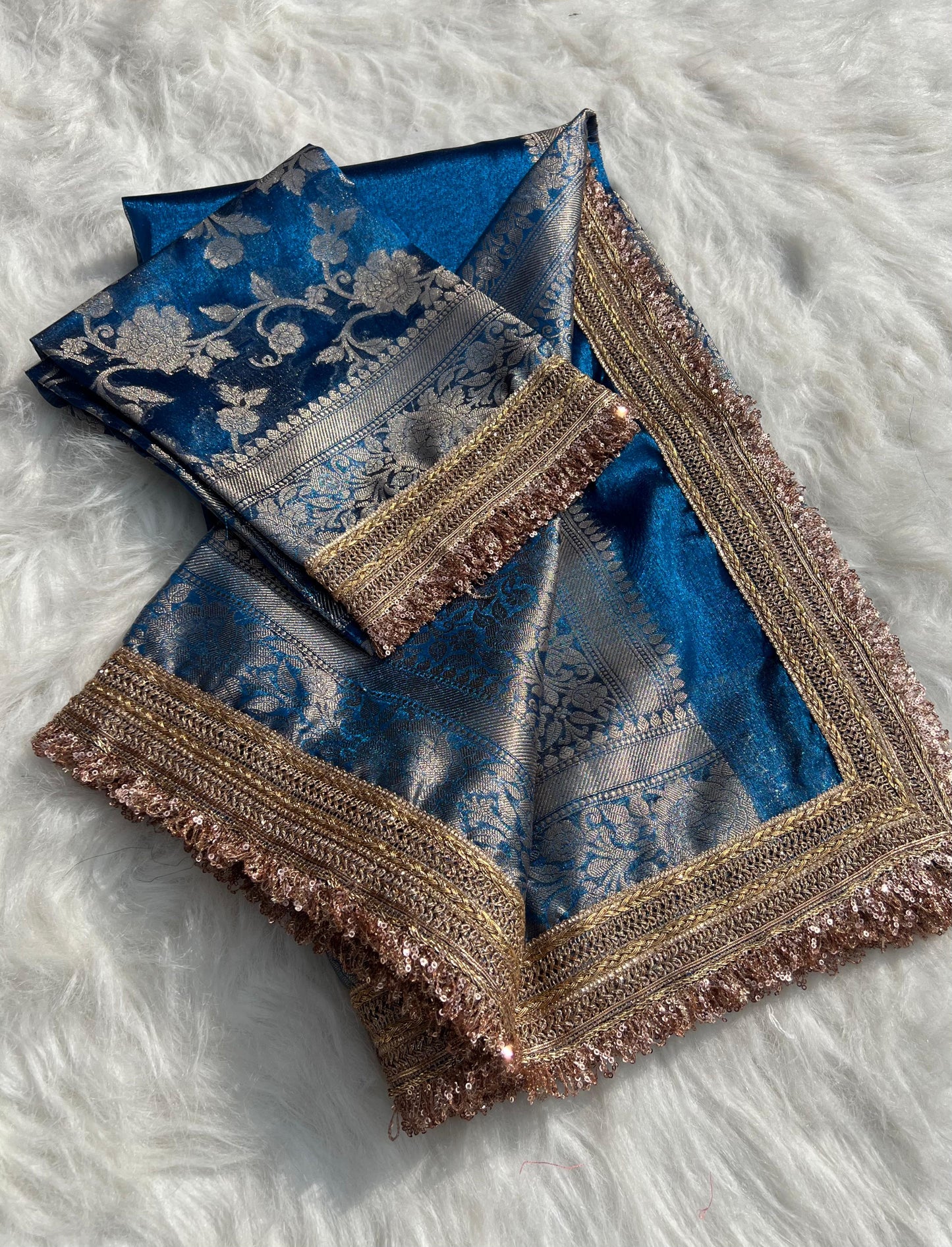 Blue saree with gold and silver embroidery on a white textured background