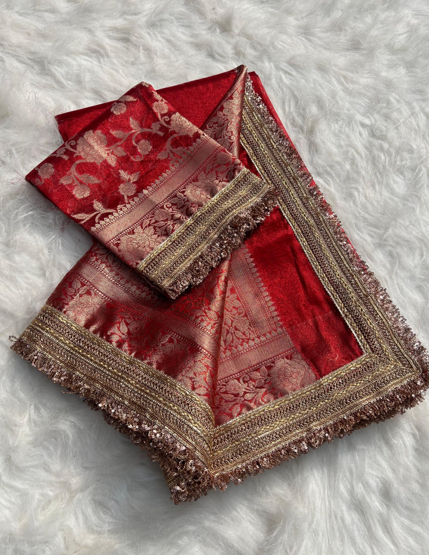 Red embroidered fabric with gold border on a white fluffy background