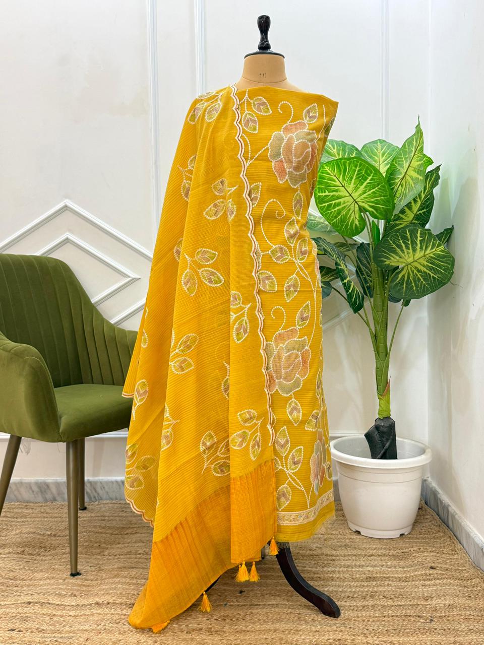 Yellow embroidered dress on a mannequin with a plant in the background