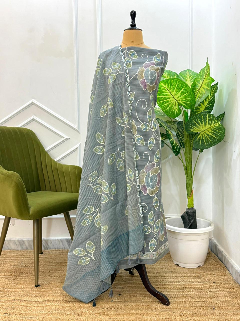 Gray floral patterned scarf on a mannequin with a green chair and plant in the background