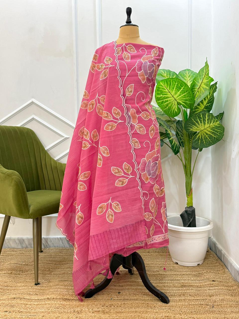 Pink floral patterned fabric draped over a mannequin with a green chair and plant in the background.