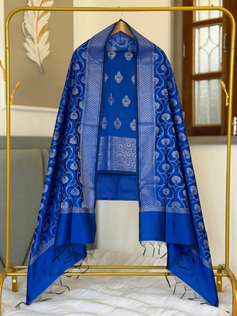Blue patterned fabric draped over a gold stand with a neutral background