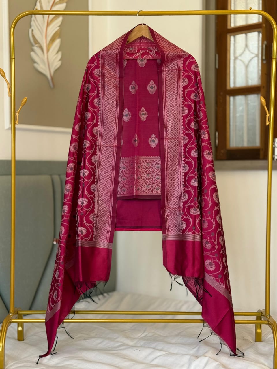 Pink patterned scarf on a gold rack with a neutral background