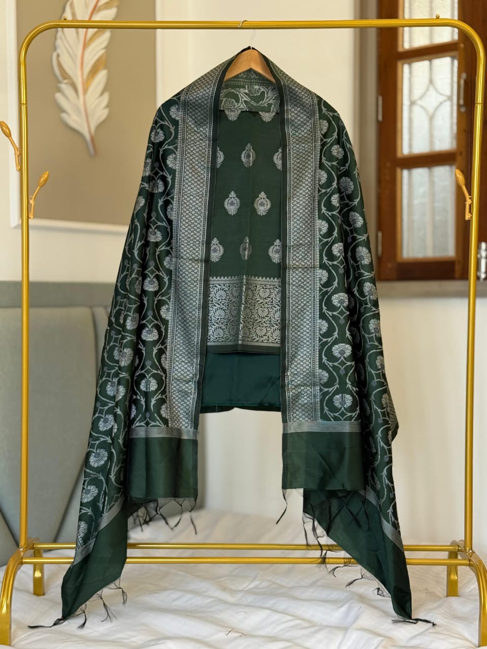 Green traditional outfit with a matching dupatta on a gold stand.