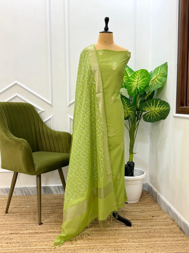 Green saree on a mannequin with a plant and chair in the background