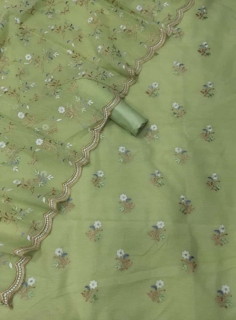 Green fabric with floral embroidery and a rolled-up section on a matching green background