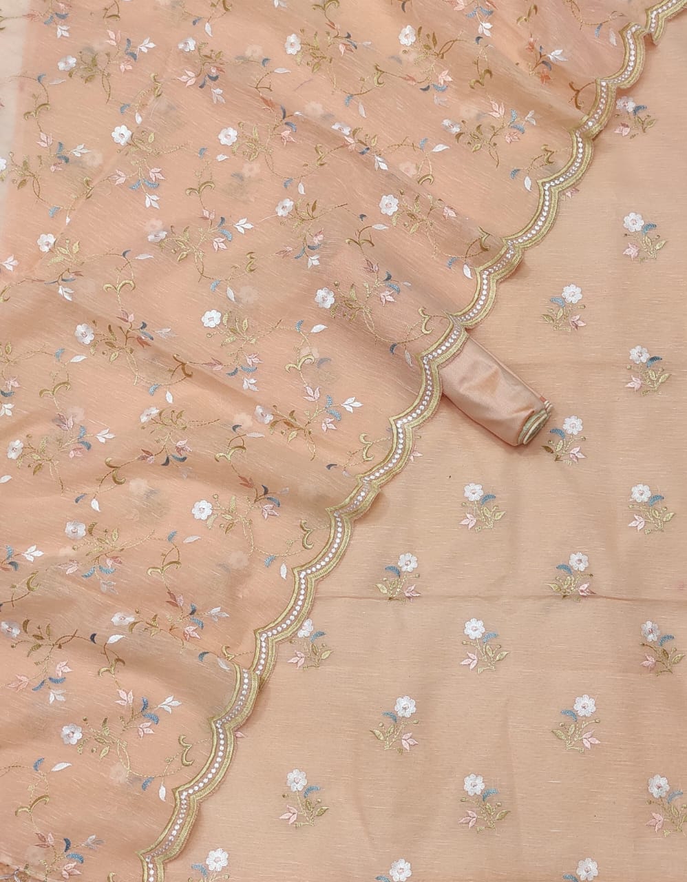Delicate peach fabric with floral patterns and decorative border