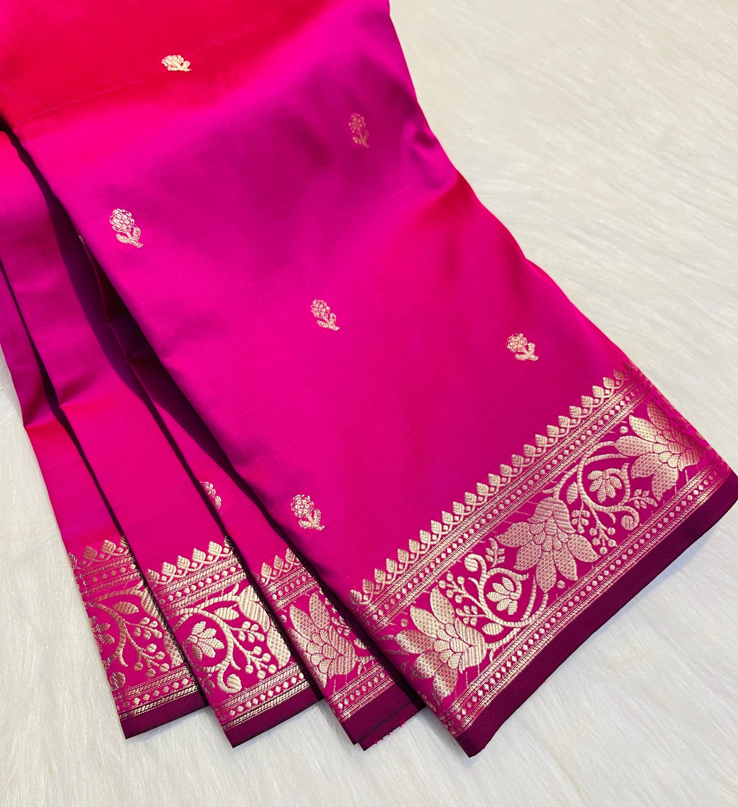 Pink saree with gold border on a light wooden surface