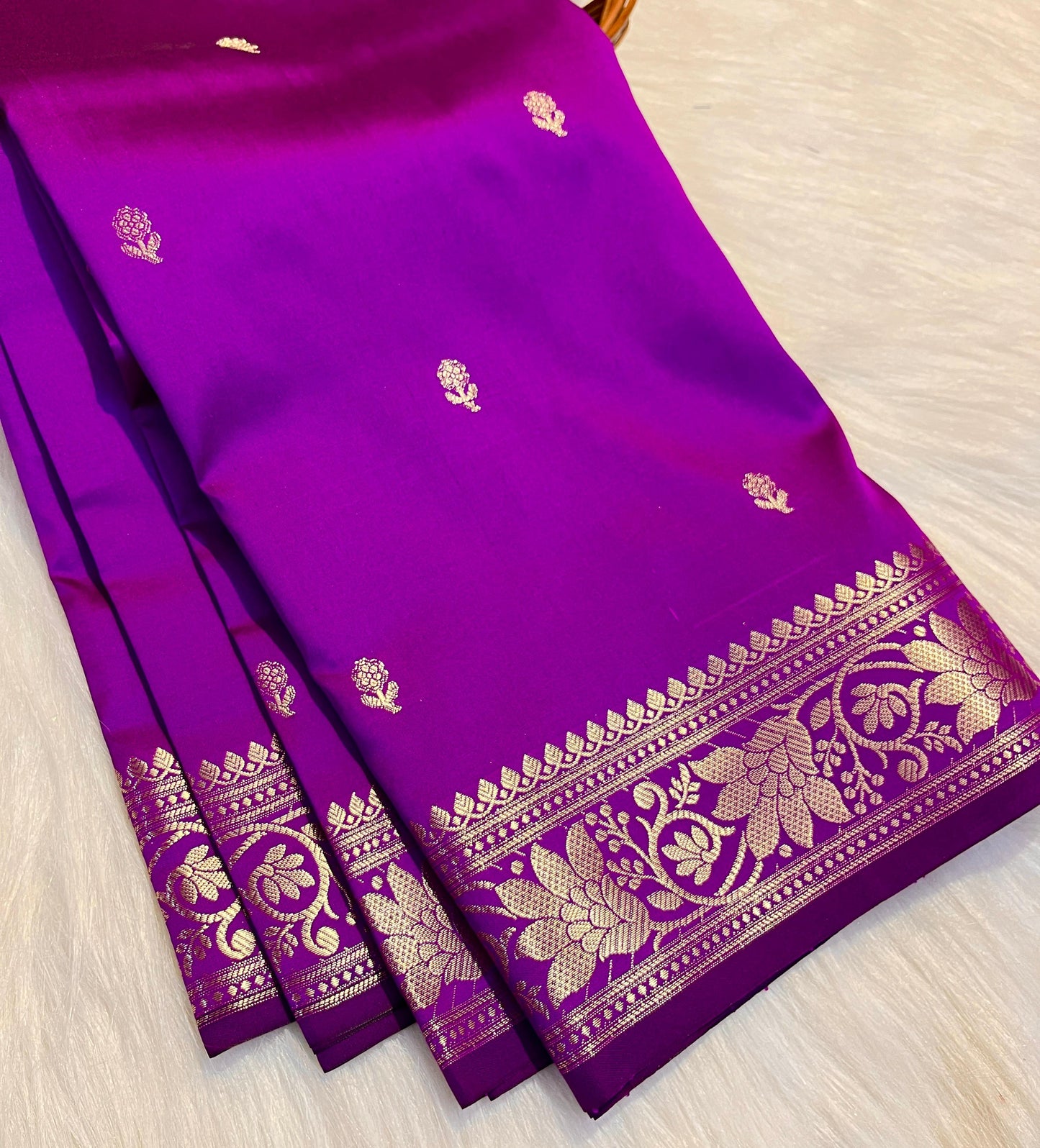 Purple saree with gold border on a light wooden surface