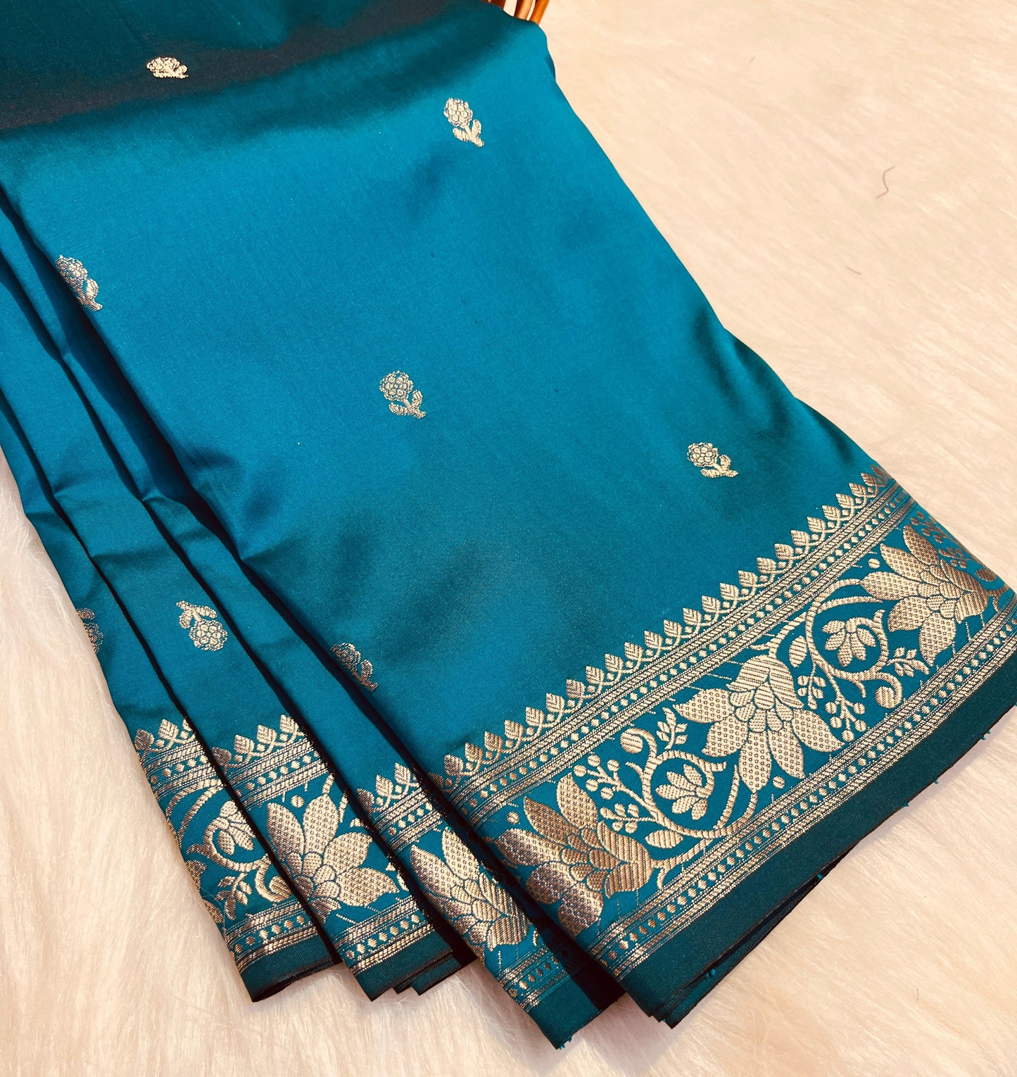 Blue saree with gold embroidery on a light wooden surface