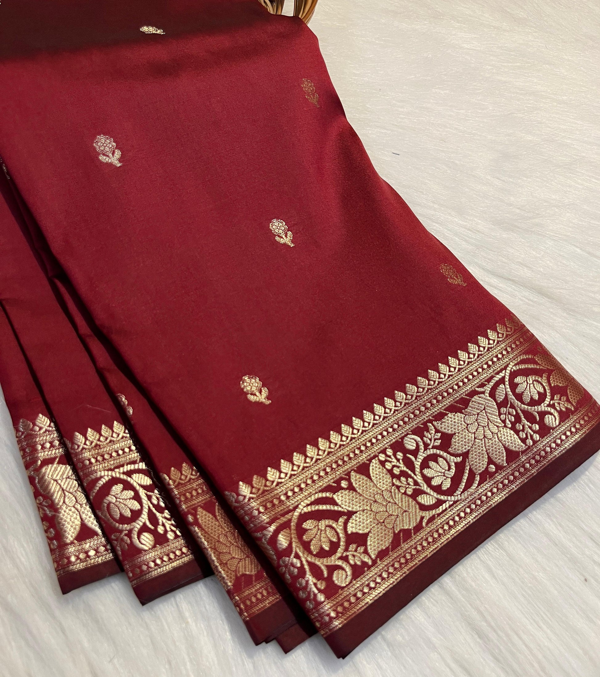Maroon saree with gold embroidery on a light gray background