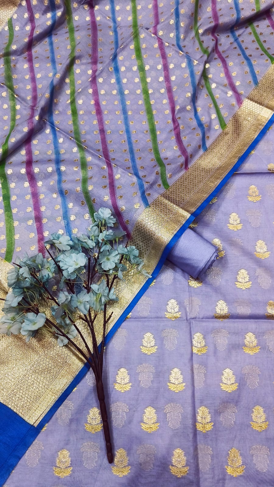Purple saree with gold patterns and a decorative border, accompanied by small plants.