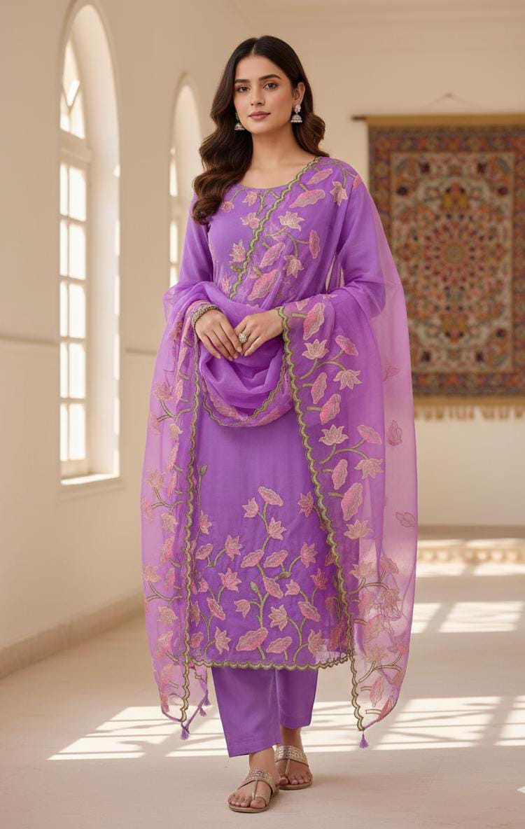 Woman wearing a purple traditional outfit with a matching dupatta in a bright room.