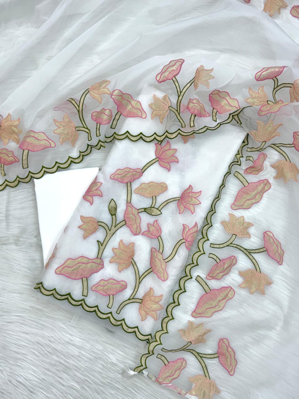 White fabric with pink floral embroidery on a light wooden surface