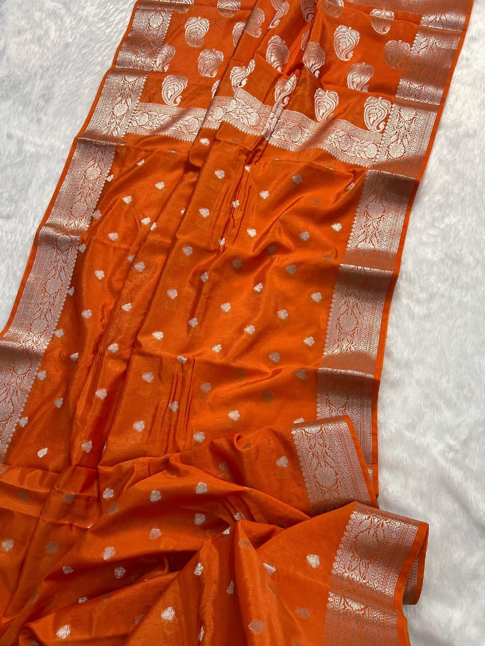 Orange saree with white patterns on a light gray background