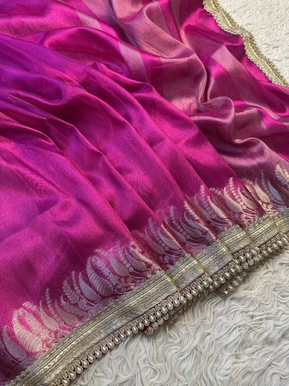 Close-up of a pink fabric with intricate gold embroidery on a textured surface