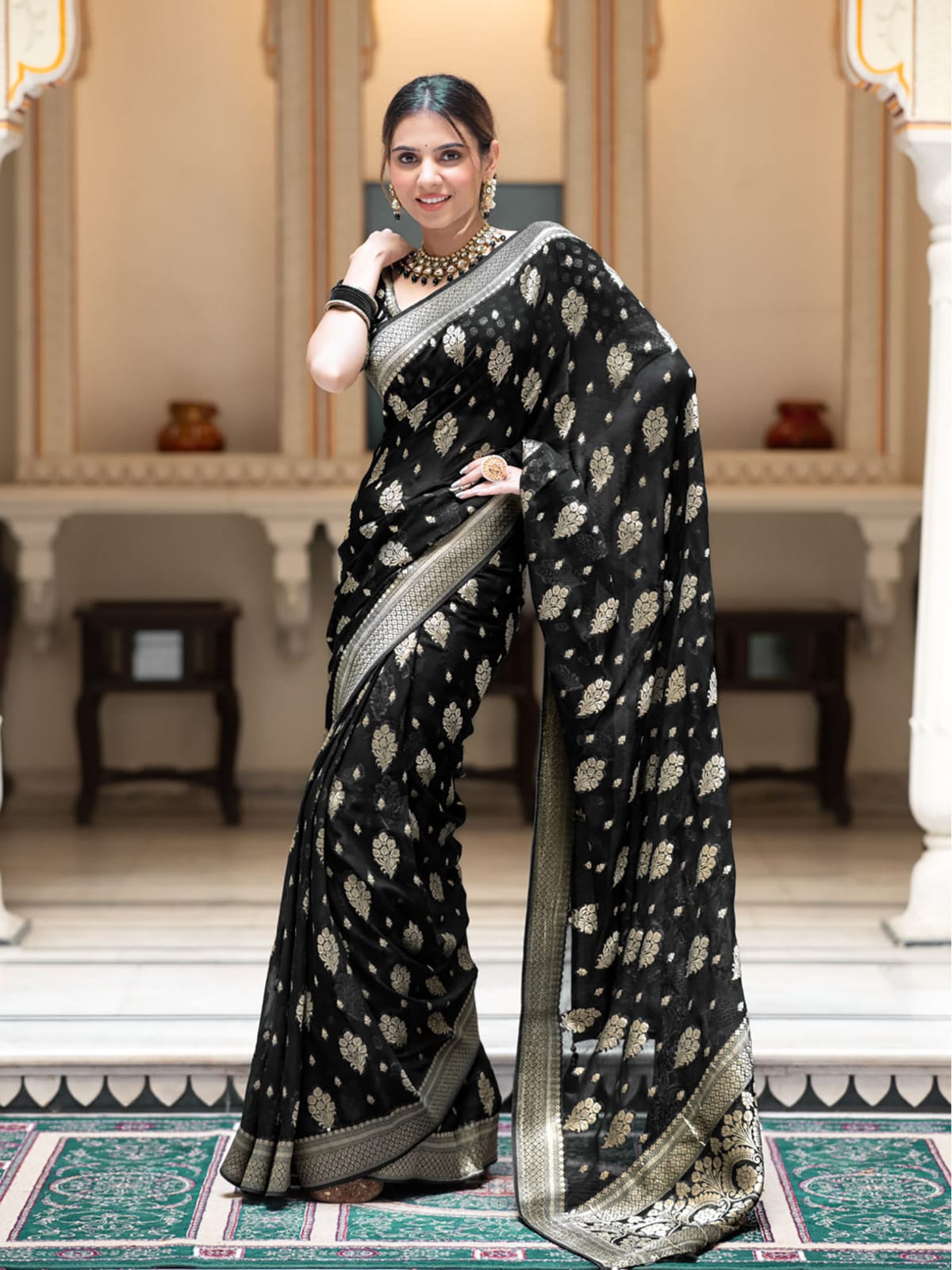 Woman wearing a black saree with white patterns in an elegant indoor setting
