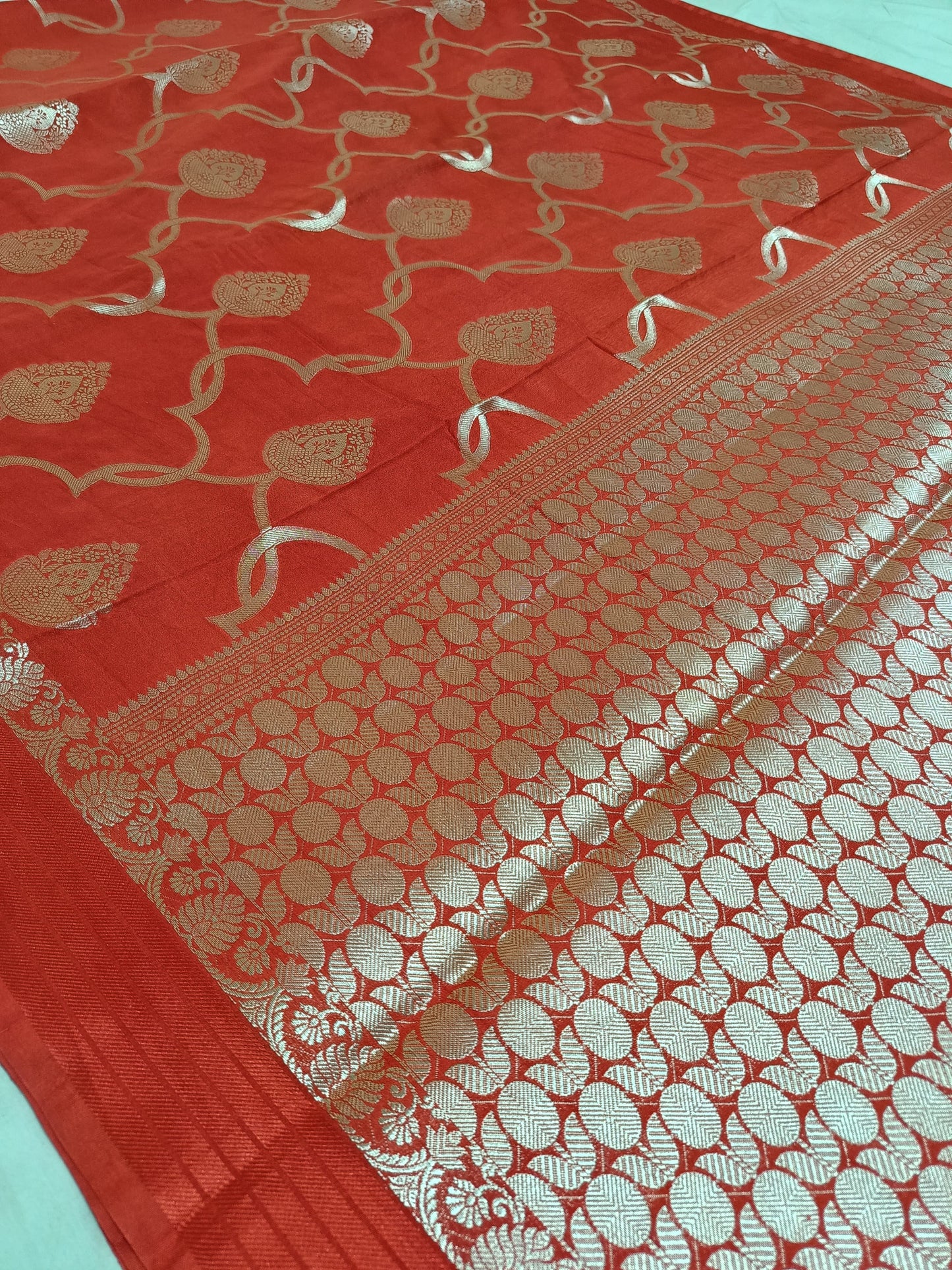 Red fabric with gold and white patterns on a light blue background