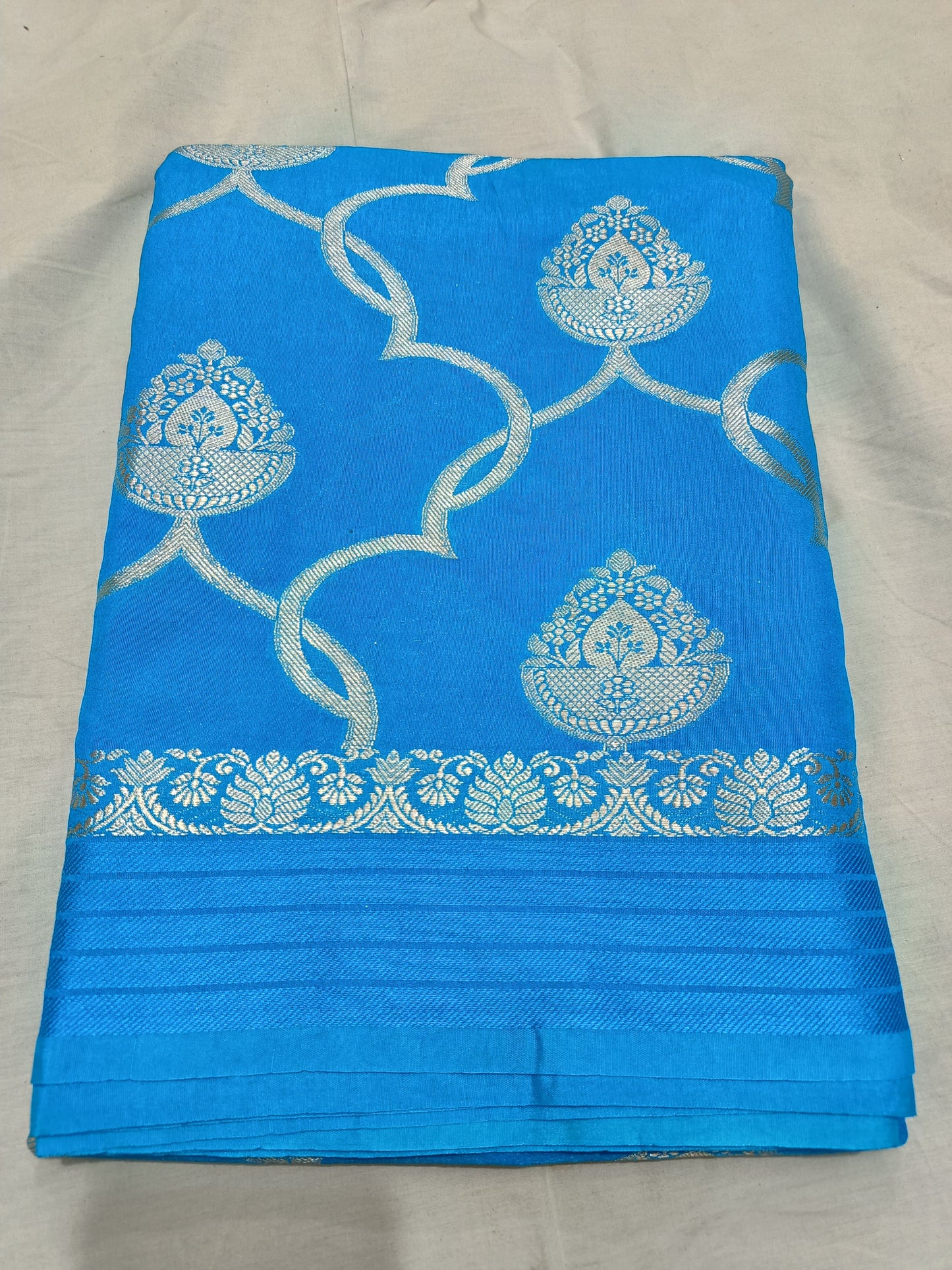 Blue fabric with silver embroidery on a light gray background