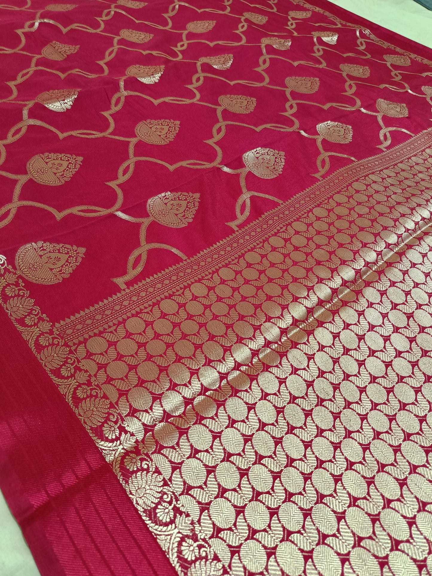 Red saree with gold leaf patterns on a white background