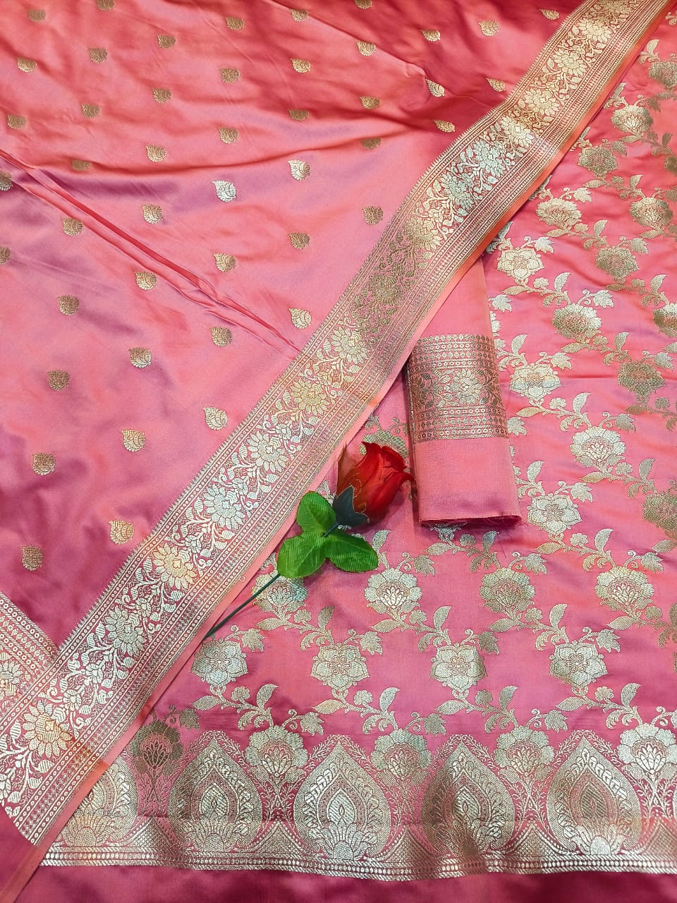 Pink saree with gold embroidery and a matching blouse on a pink background