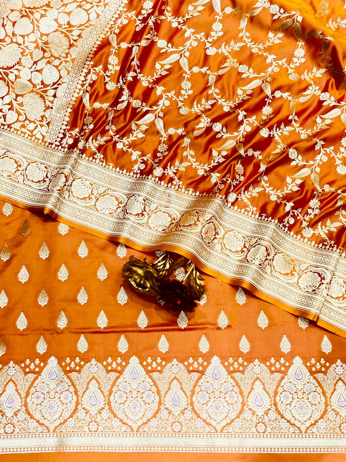 Orange saree with white intricate patterns and a gold border