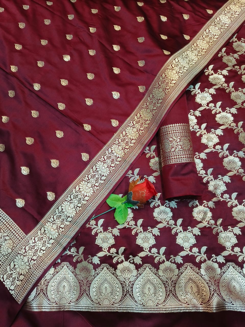 Maroon saree with gold embroidery and a floral pattern, accompanied by a small decorative item.
