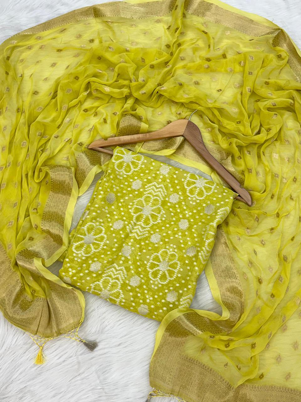 Yellow baby romper with floral pattern on a white background, draped with a matching yellow scarf.