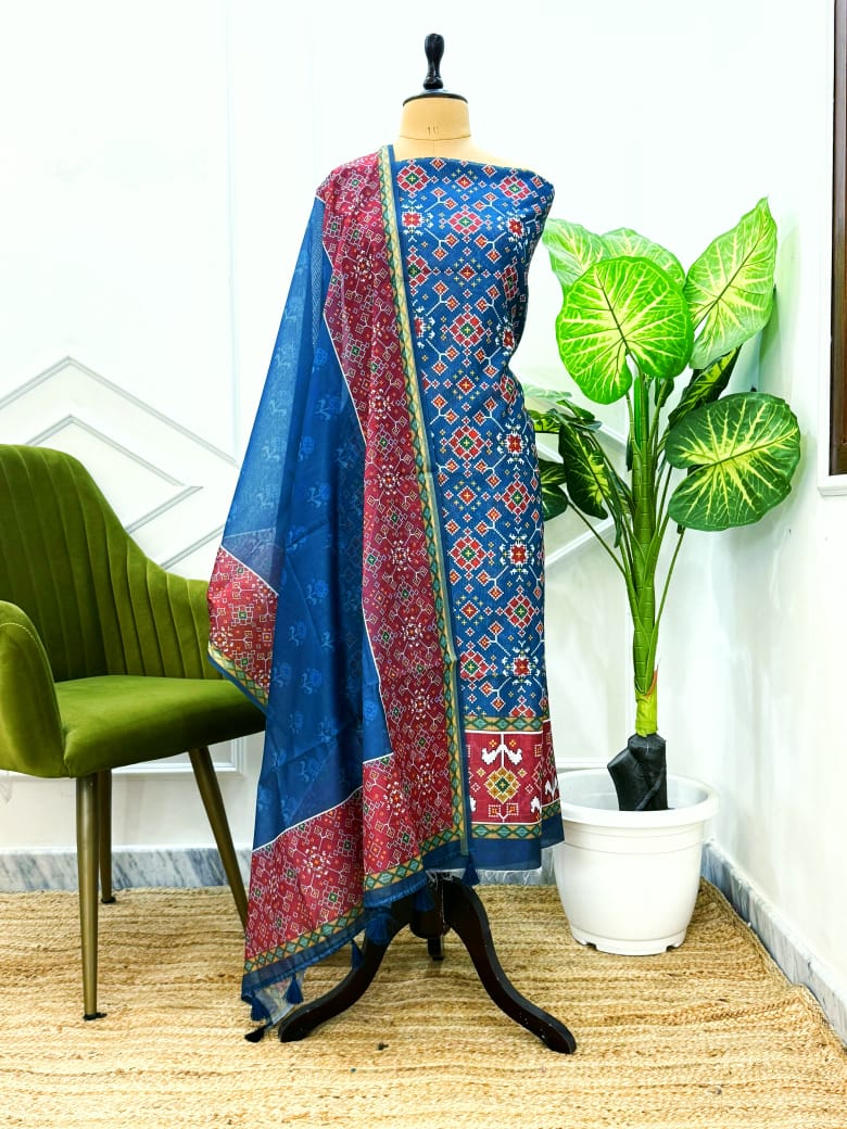 Traditional blue and red patterned fabric on a mannequin with a green chair and plant in the background