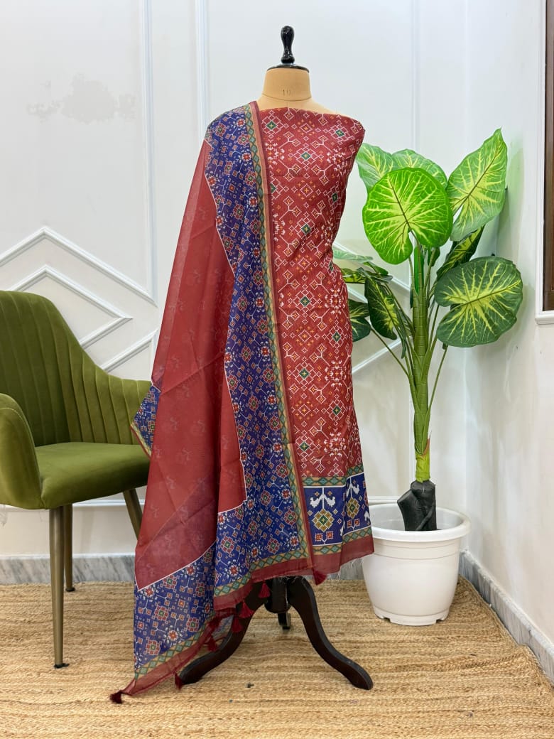 Red and blue patterned fabric on a mannequin with a green chair and plant in the background