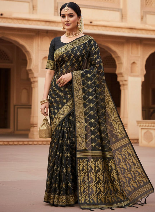 Woman wearing a black and gold saree in an architectural setting