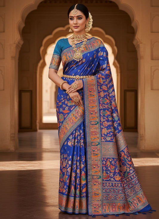Woman wearing a traditional blue saree with intricate patterns in an architectural setting