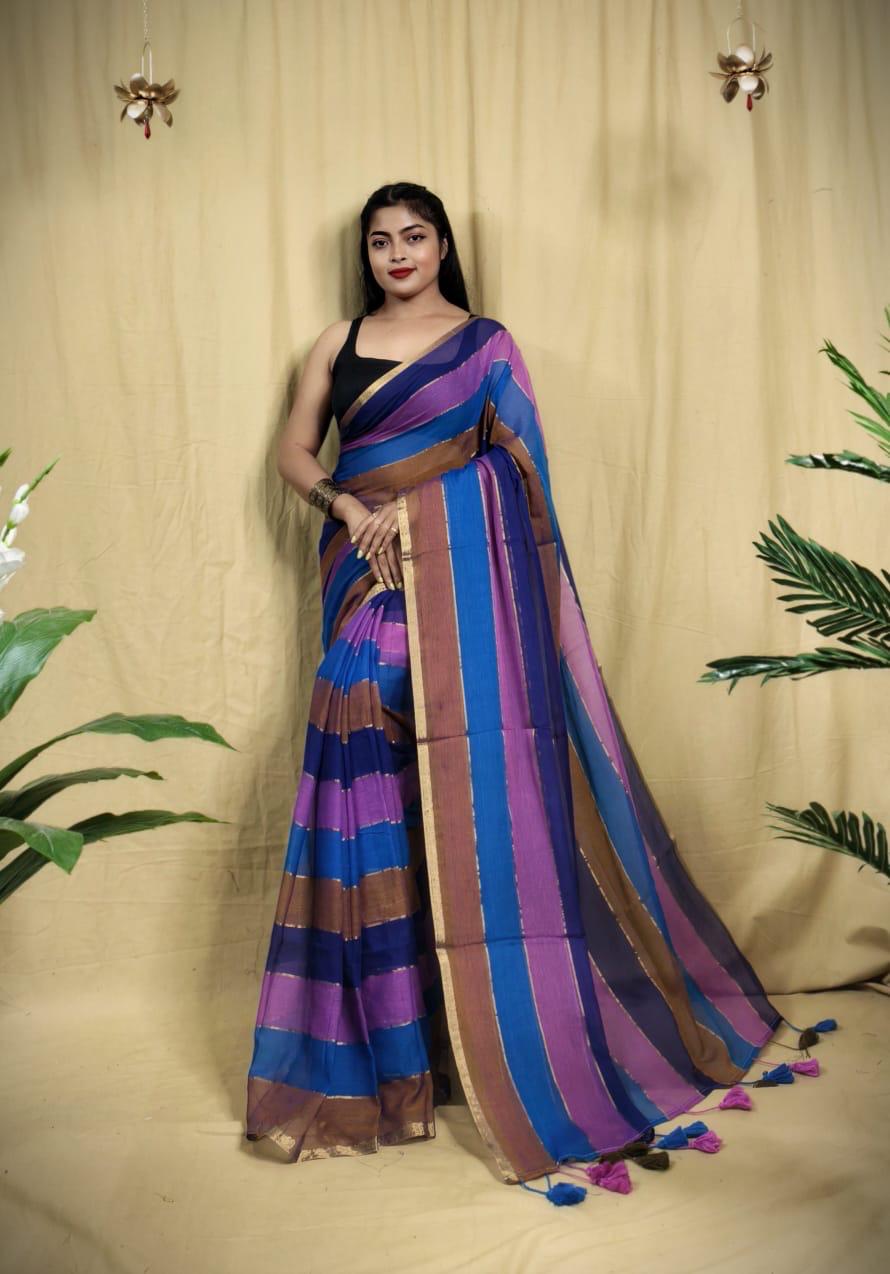 Woman wearing a colorful striped saree against a beige curtain background
