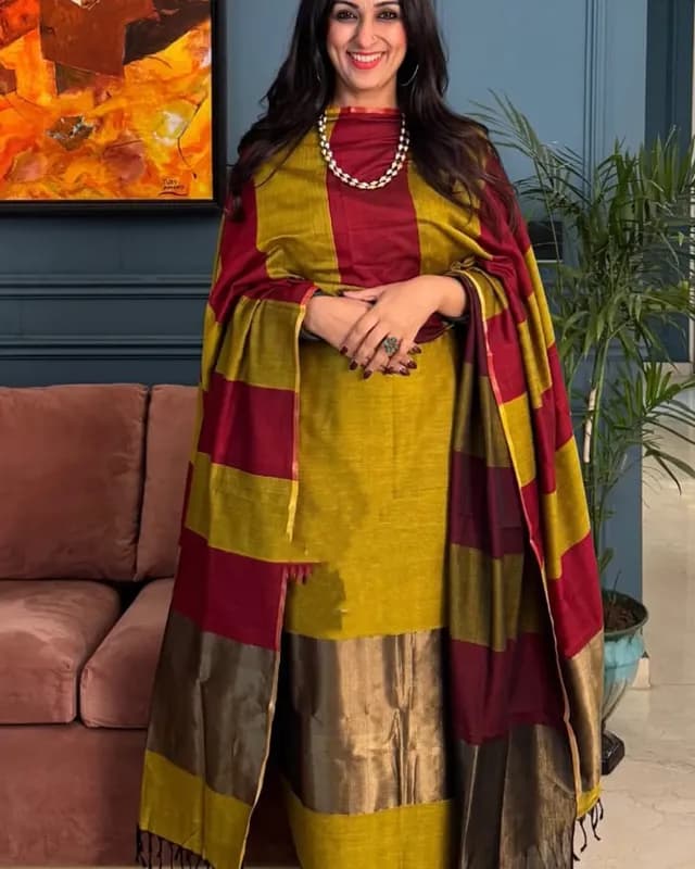 Woman wearing a traditional outfit with maroon and yellow colors in an indoor setting.