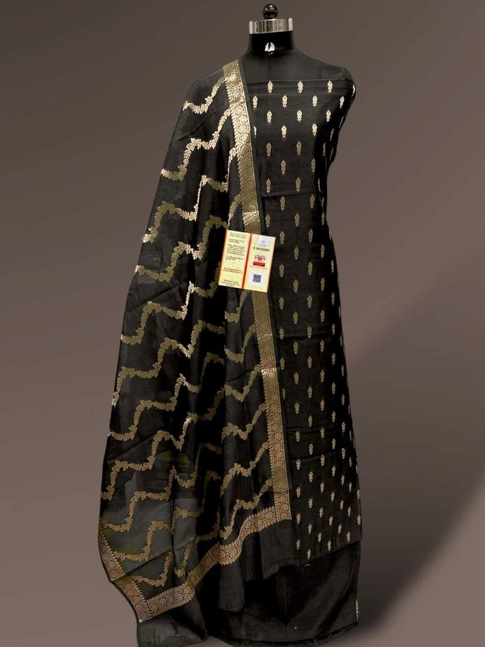 Black dress with gold patterns on a mannequin against a gray background
