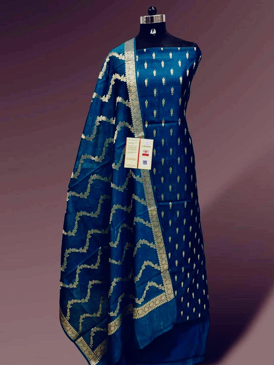 Blue saree with white patterns on a mannequin against a purple background
