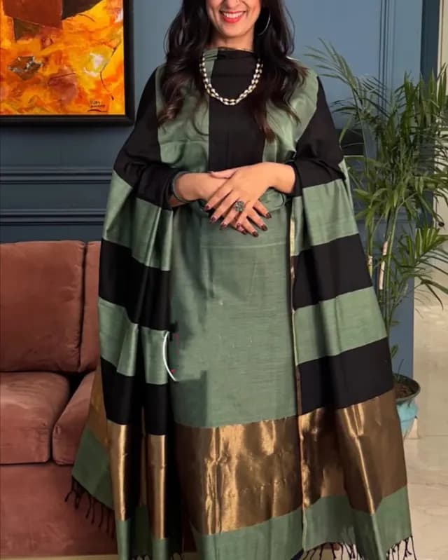 Woman wearing a green and black striped dress with a patterned shawl indoors.