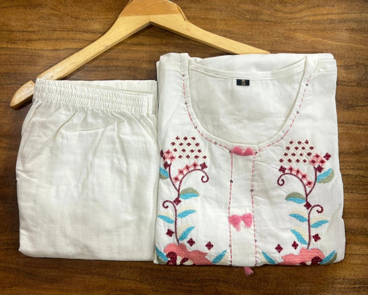 White embroidered top and shorts on a wooden hanger against a wooden background