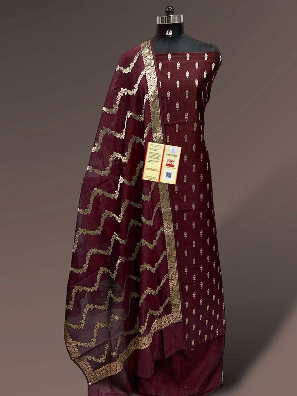 Maroon traditional outfit with gold patterns on a mannequin against a gray background